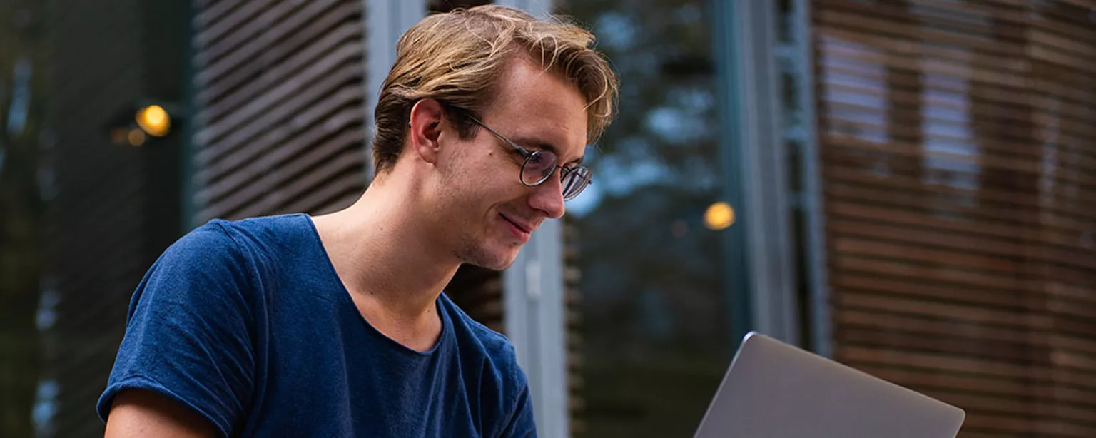 Homme avec des lunettes travaille sur un portable