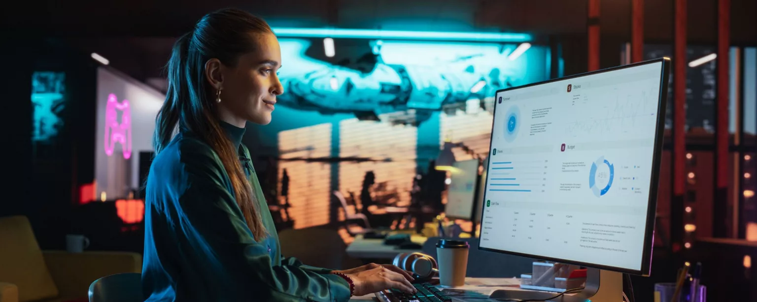 A marketing analytics professional reviews data dashboards and performance metrics on a computer screen in a colorful office setting.