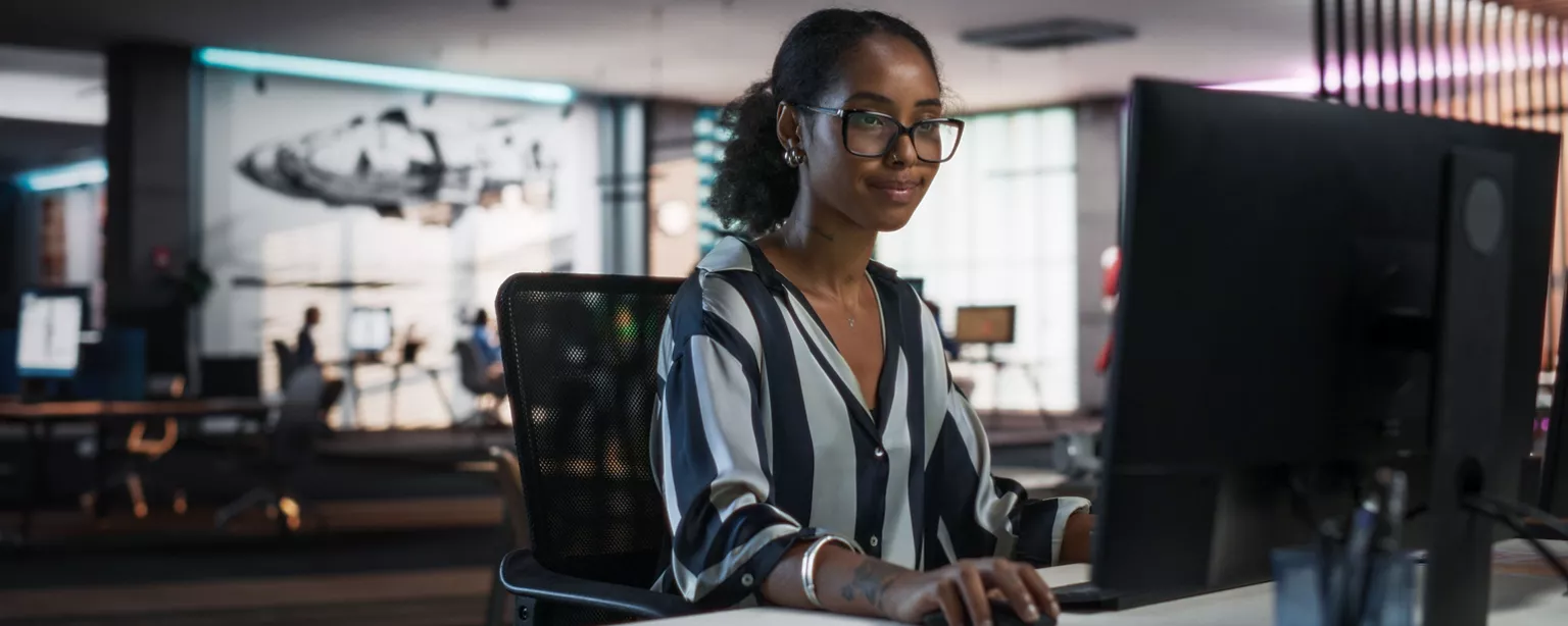 A marketing professional works at a computer in an office.