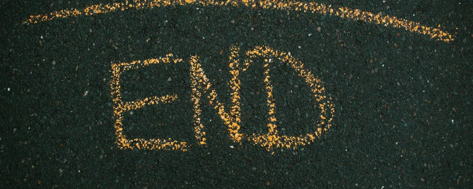 Das Wort “End” mit gelber Kreide auf Asphalt geschrieben