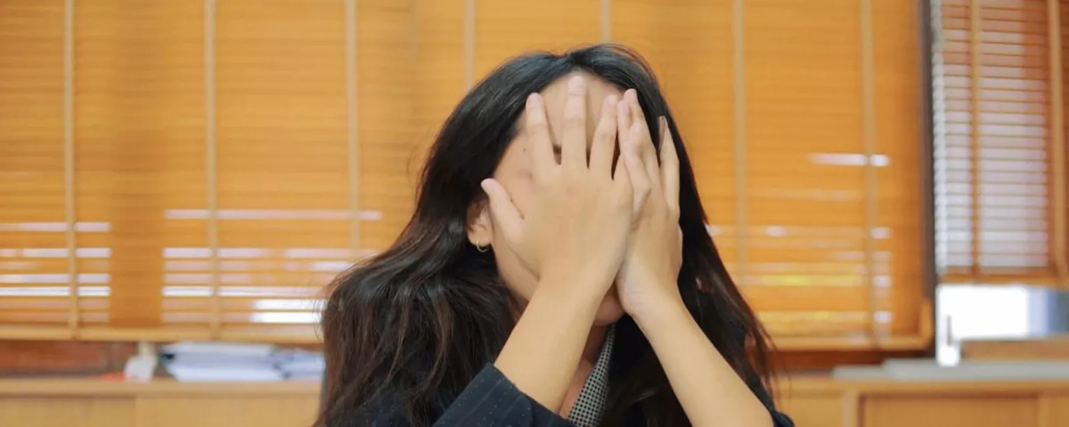 A woman covering her face with her hands. 