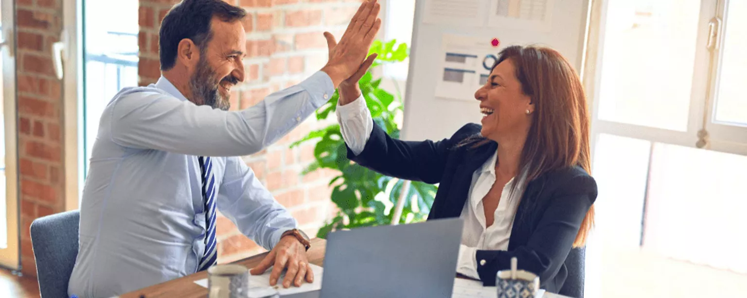 Ein Mann und eine Frau am Arbeitsplatz geben sich ein High-Five