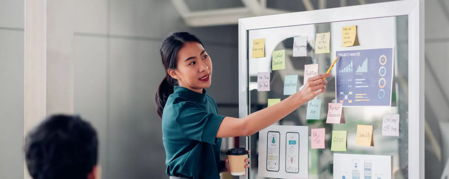 Image of woman standing next to whiteboard with charts and graphs.