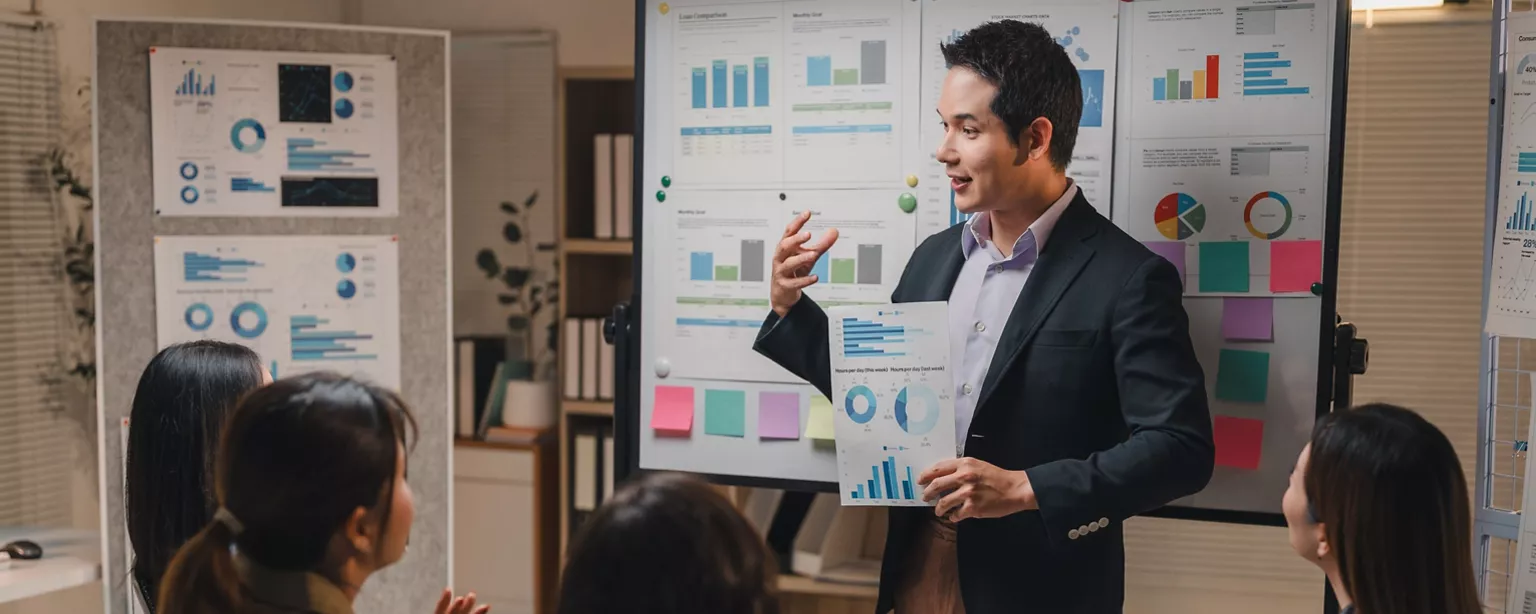 A finance professional presents data insights to colleagues during a team meeting.