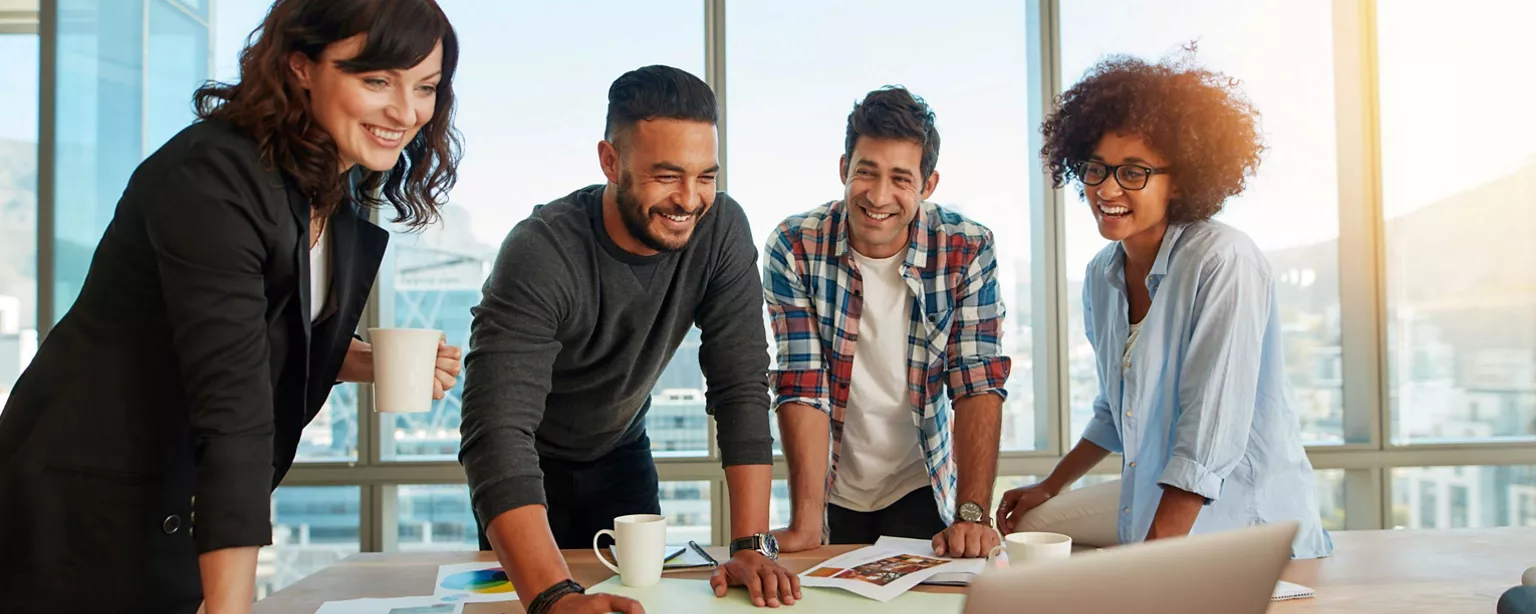 A group of creative agency employees converse at a table as they work together in a conference room.