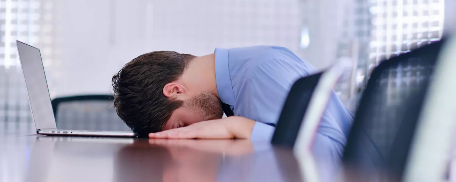 Think You'll Regret Leaving a Job? 5 Questions to Ask First — man with his head on a table who looks like he did something he regrets