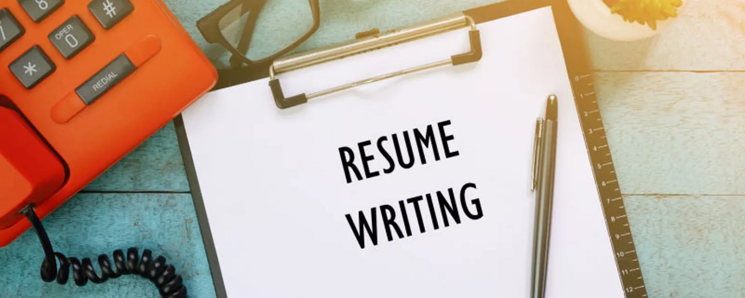 picture of a resume writing on a clipboard on a aqua-colored desk next to an orange phone.