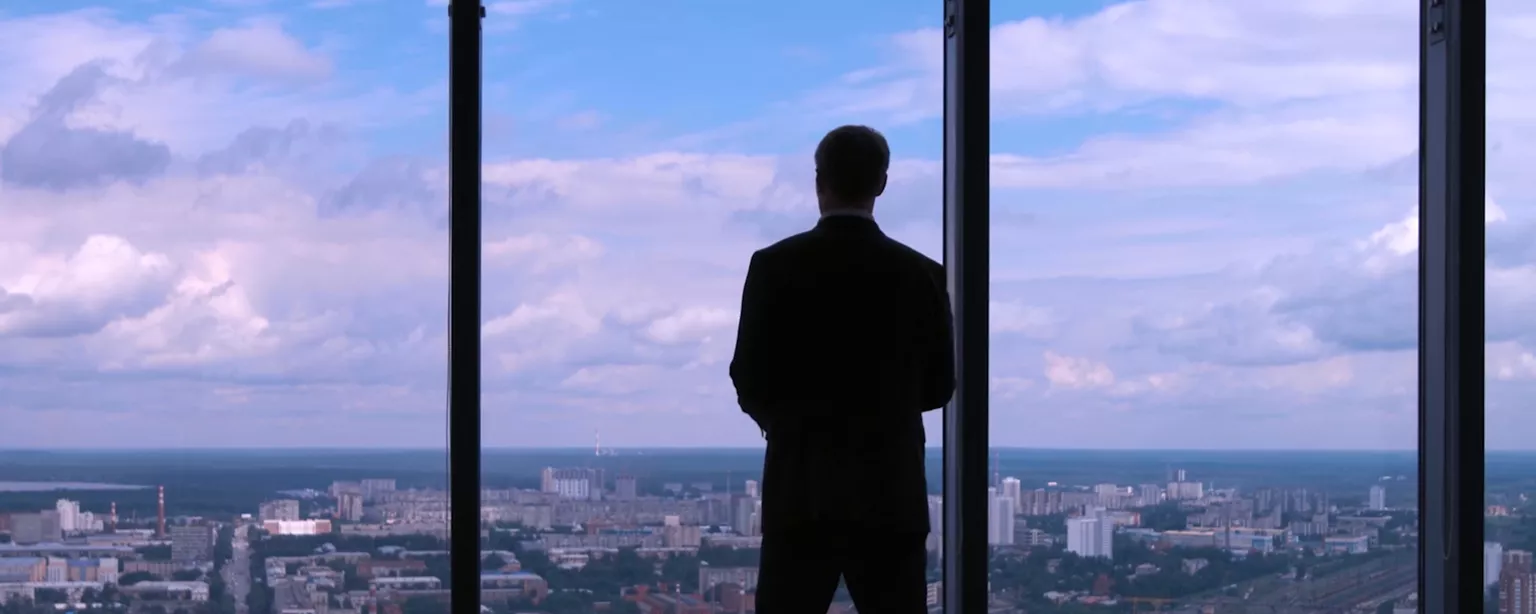 Businessman looking out office window to city below