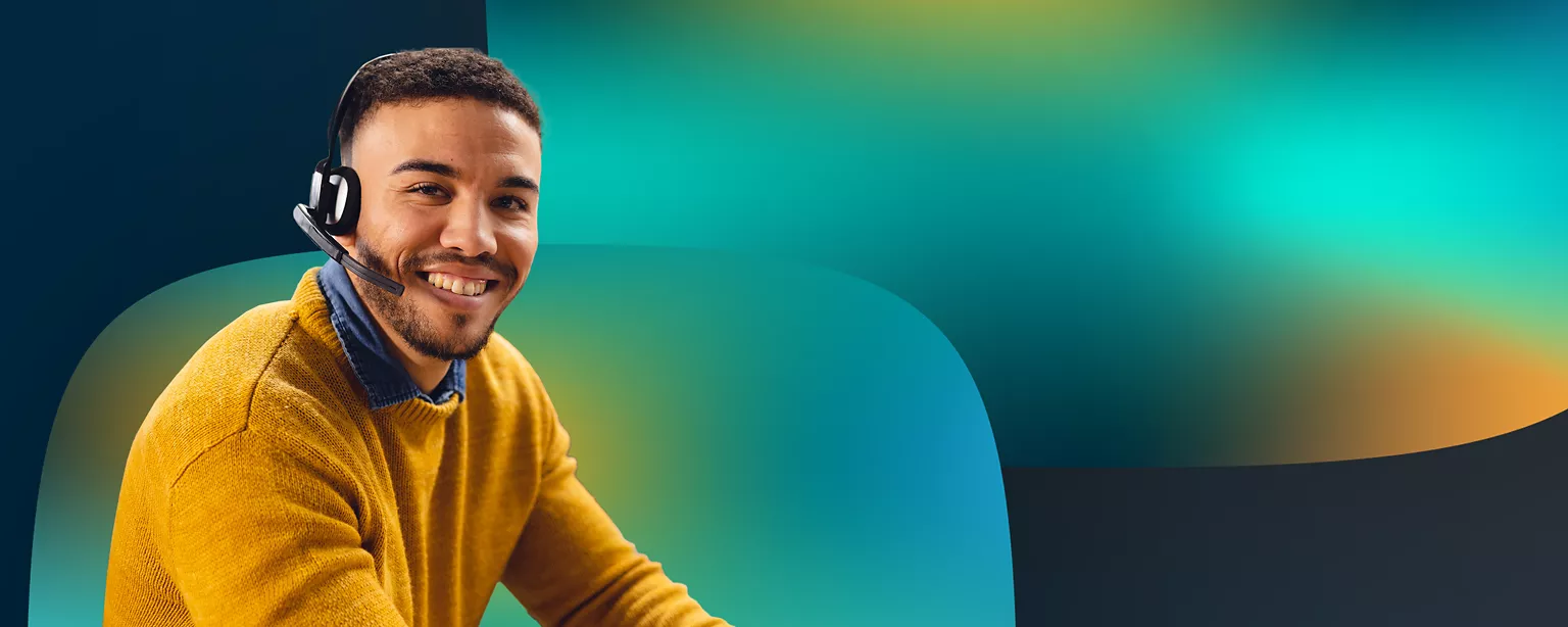 A man in a yellow sweater is wearing a headset and smiling.