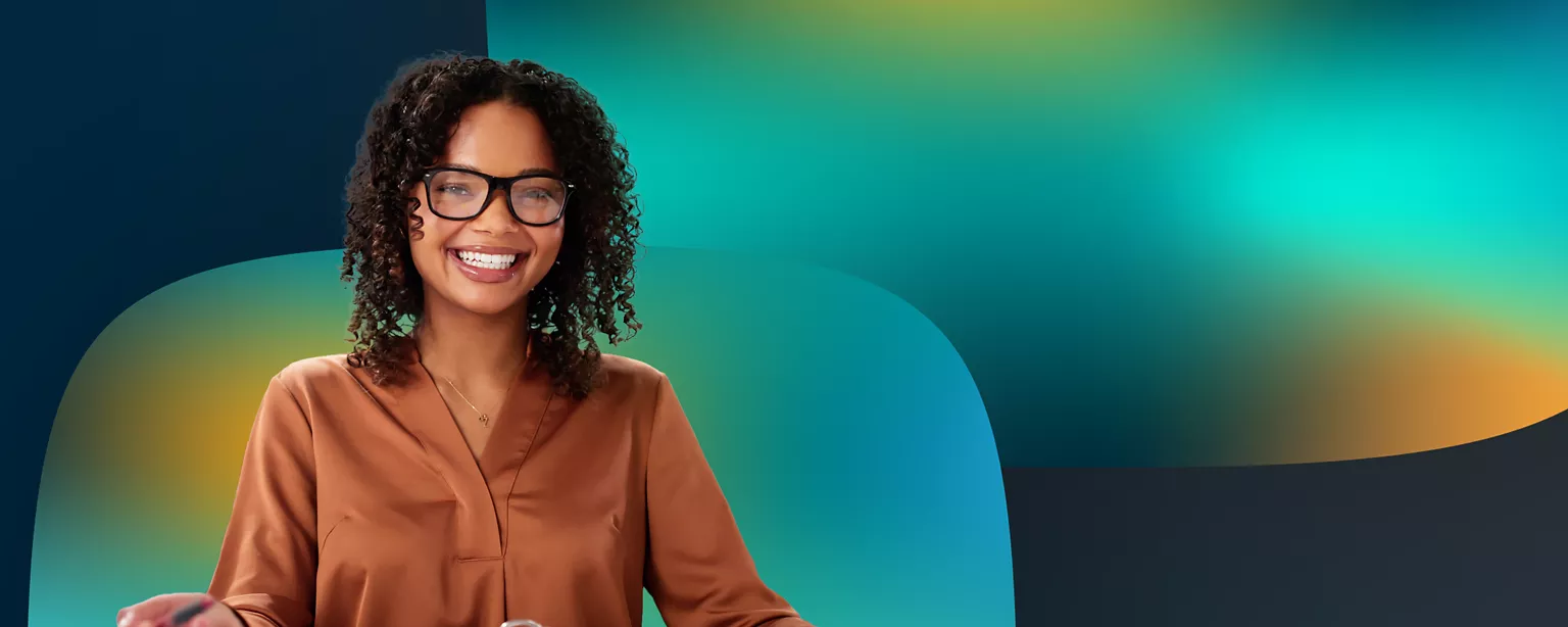 A woman in a brown shirt and wearing glasses faces forward and smiles.