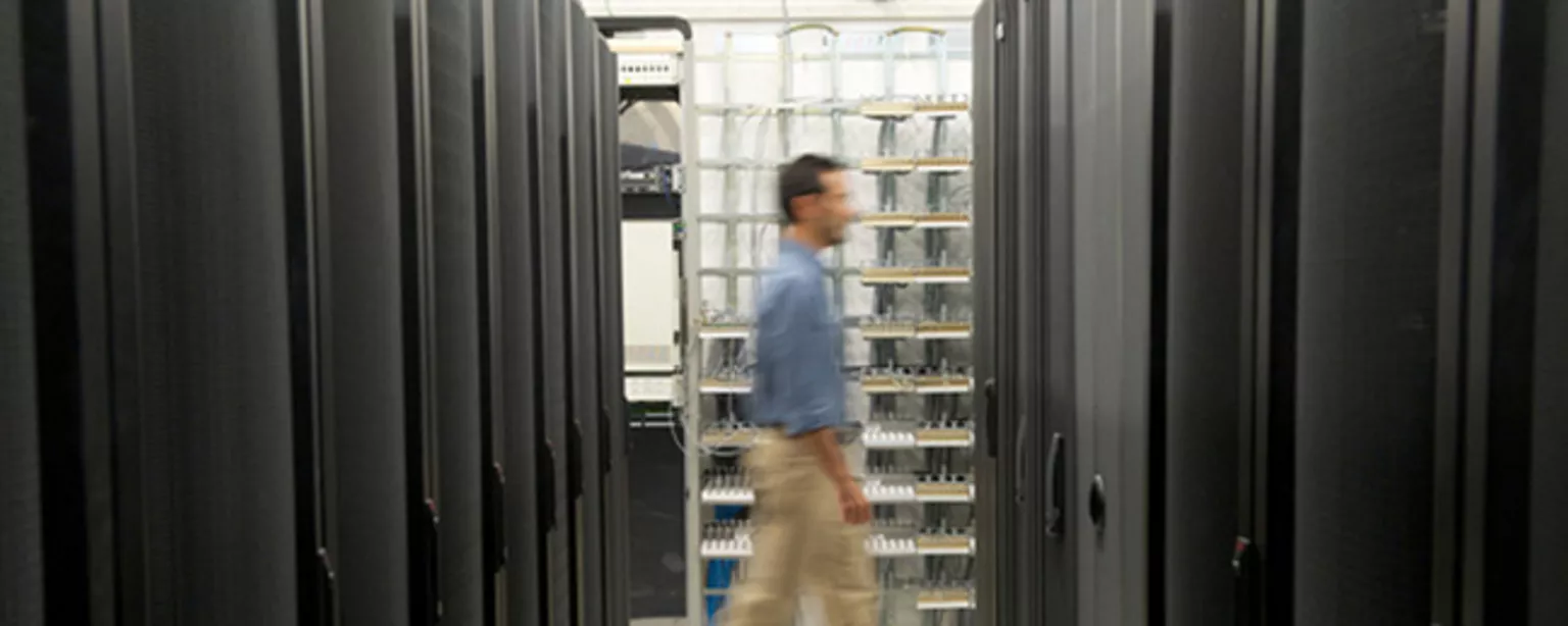 A man walking between two rows of servers.