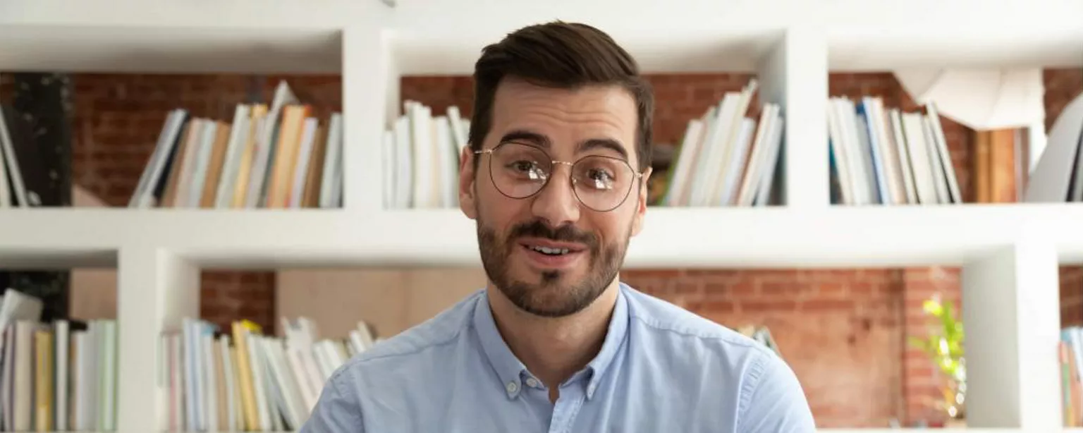 Homme faisant face à la caméra qui parle avec les bras étendus devant lui.