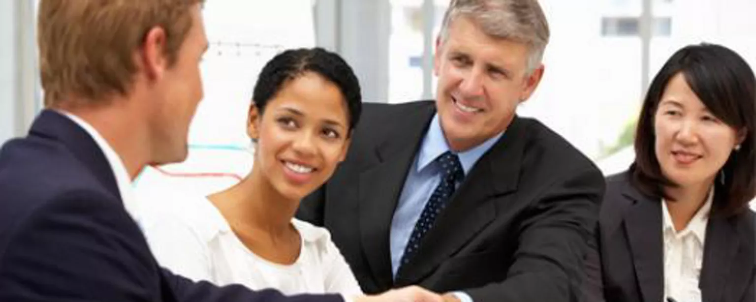 A lawyer thanks his law clerk with a handshake with 2 lawyers smile