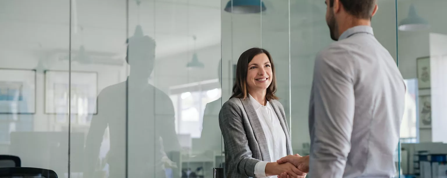 A Human Resources manager shakes hands with a recently hired additon to the team.