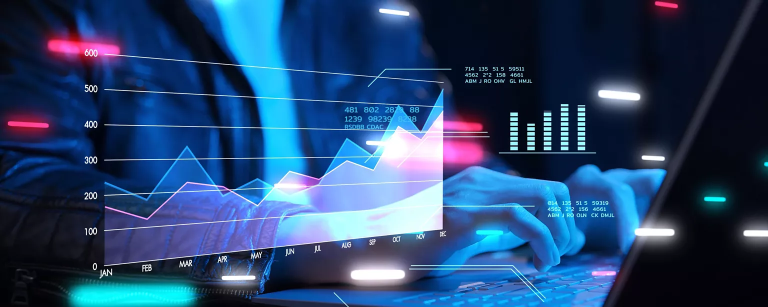 Hands on a laptop with overlaid line and bar charts tracking monthly metrics, symbolizing a data-driven modern finance function.