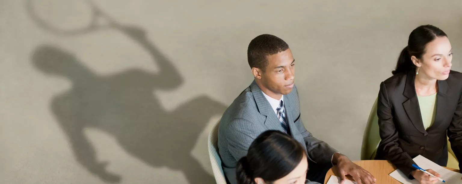 Male colleague sits at a desk with a tennis player shadow behind him