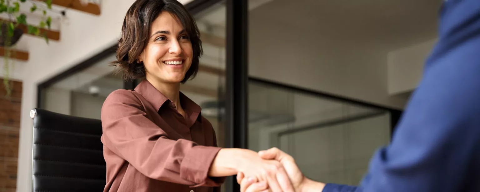 A job candidate shakes hand with a hiring manager as she prepares to begin her third interview.