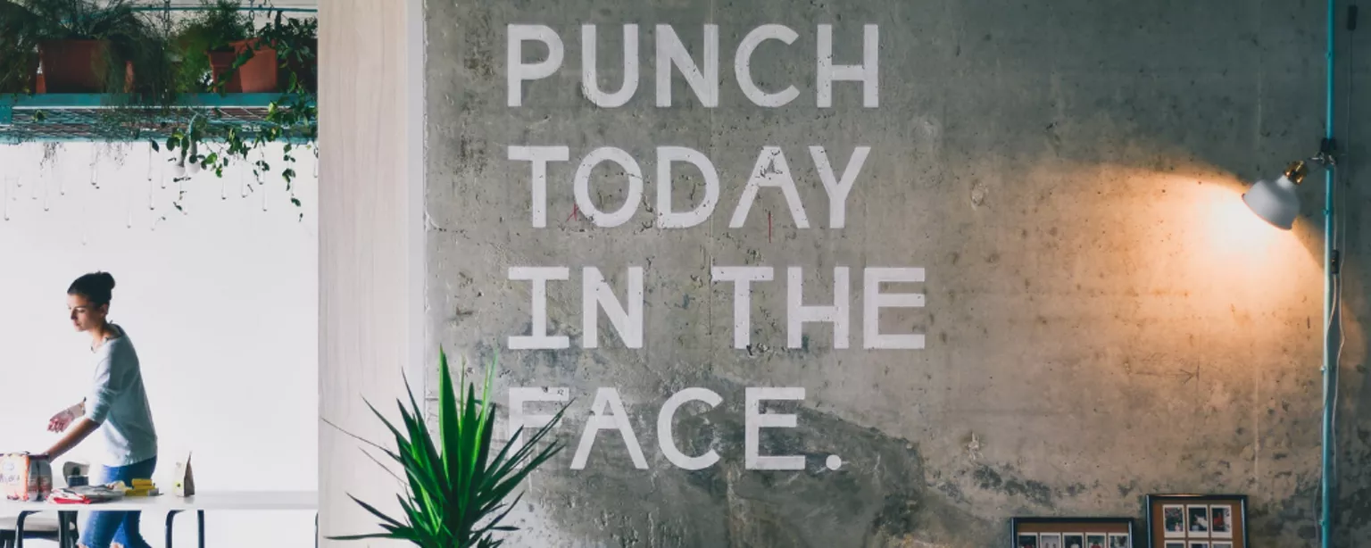 Großer offener Arbeitsraum mit Wandbeschriftung “Punch today in the face”