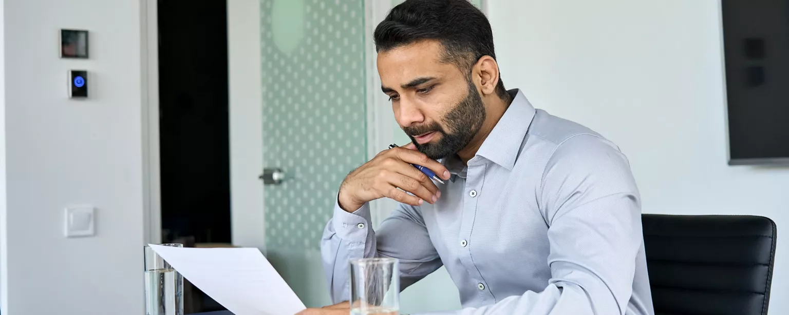 A legal professional reviews his resume at his desk.