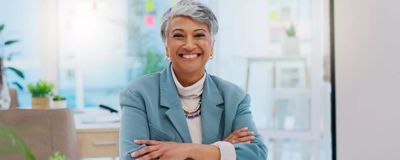 A woman in a position of leadership smiles while sitting at her desk.