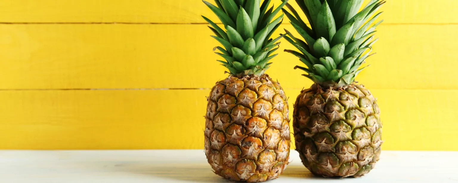Two pineapples against a yellow background.