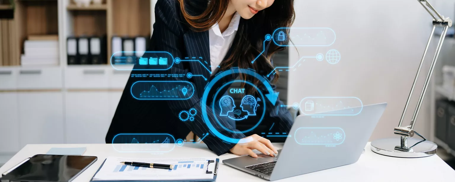 A businesswoman works on a laptop, surrounded by futuristic graphics representing data analytics, AI and communication.