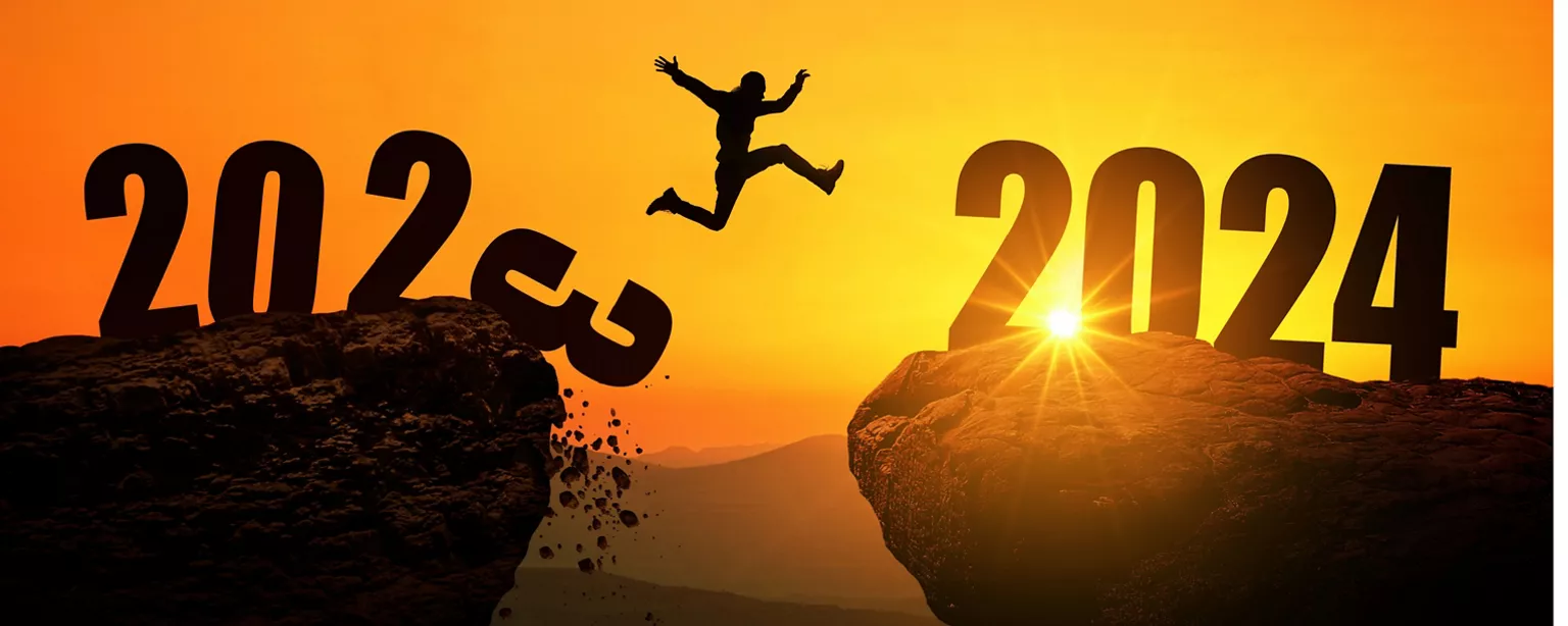 A person jumping over the gap between two cliffs at sunset, representing the transition between 2023 and 2024.