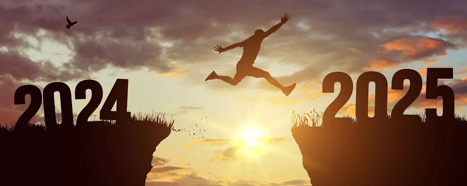 A person jumping over the gap between two cliffs at sunset, representing the transition between 2024 and 20255