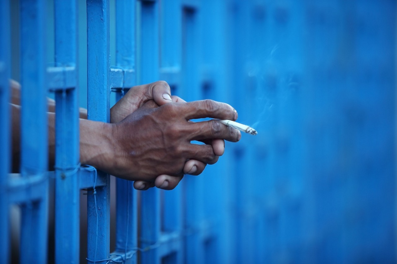 Imagem ilustrativa de detento com cigarro