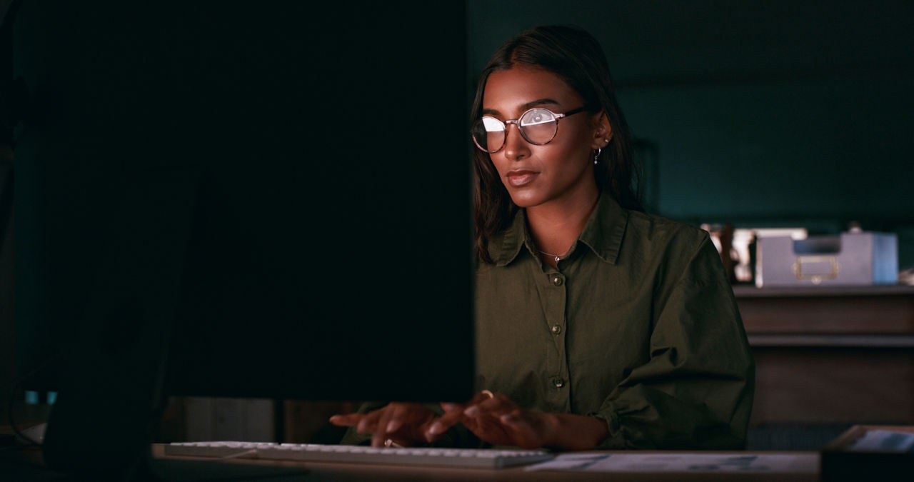 woman sitting in a dark office working on a computer