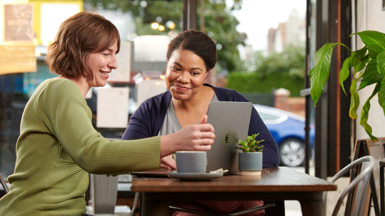 Two women sitting in a cafe looking at a computer