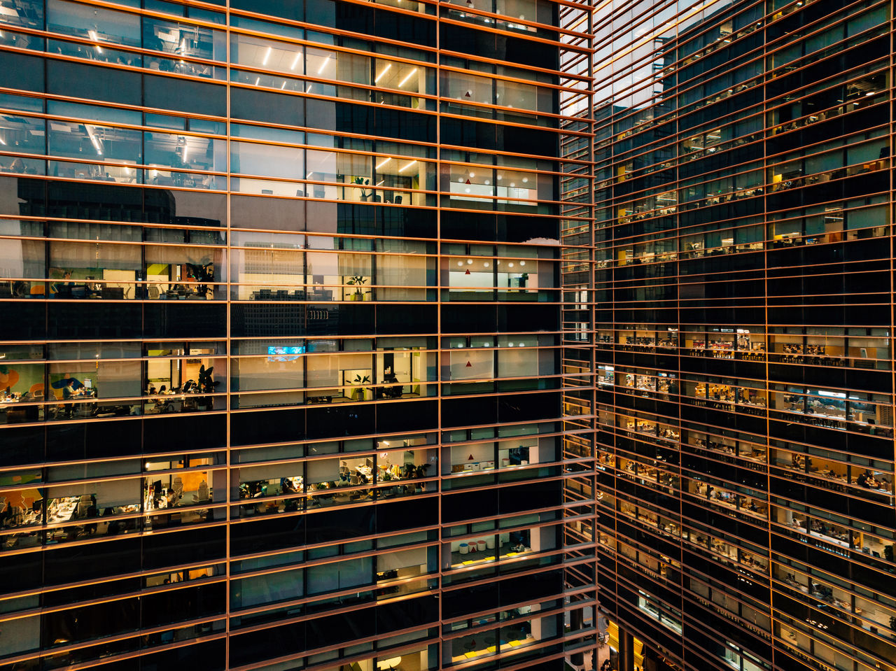an view of the outside of an office building with lights on each floor and people working