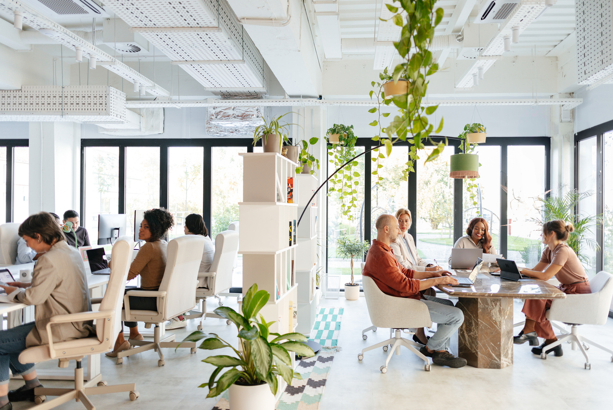 A bright and vibrant co-working office featuring diverse professionals collaborating, immersed in an open and green workplace.