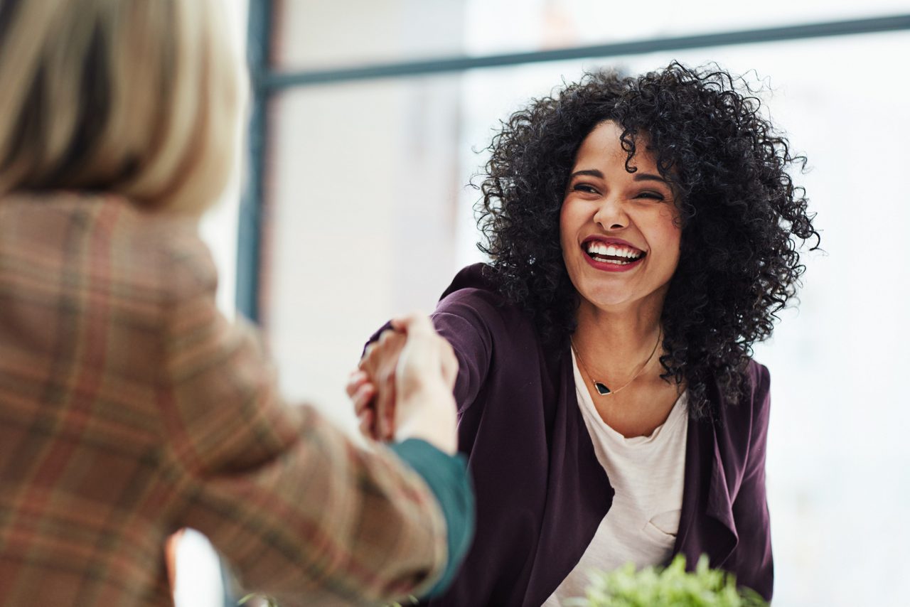 Woman shaking hand of another woman at work