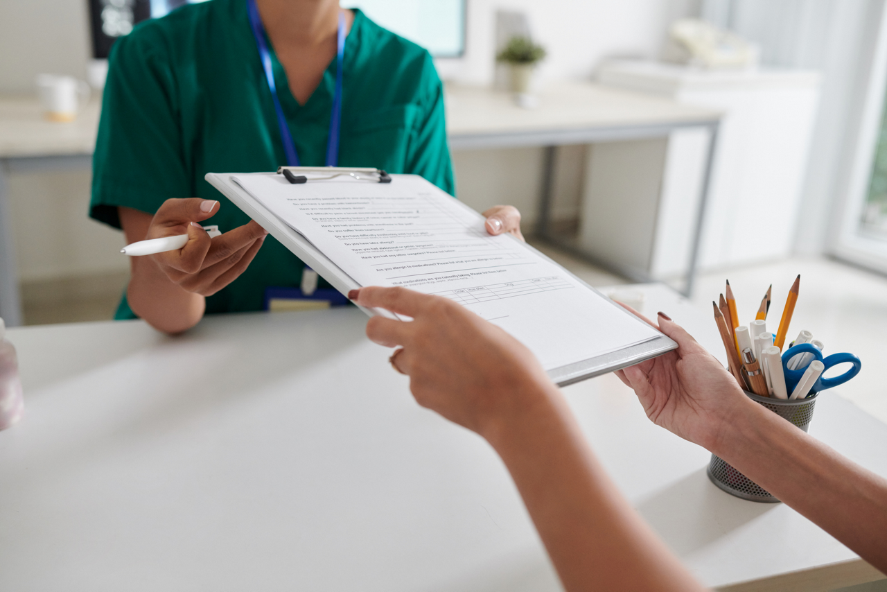 Patient giving filled questionnaire to medical nurse