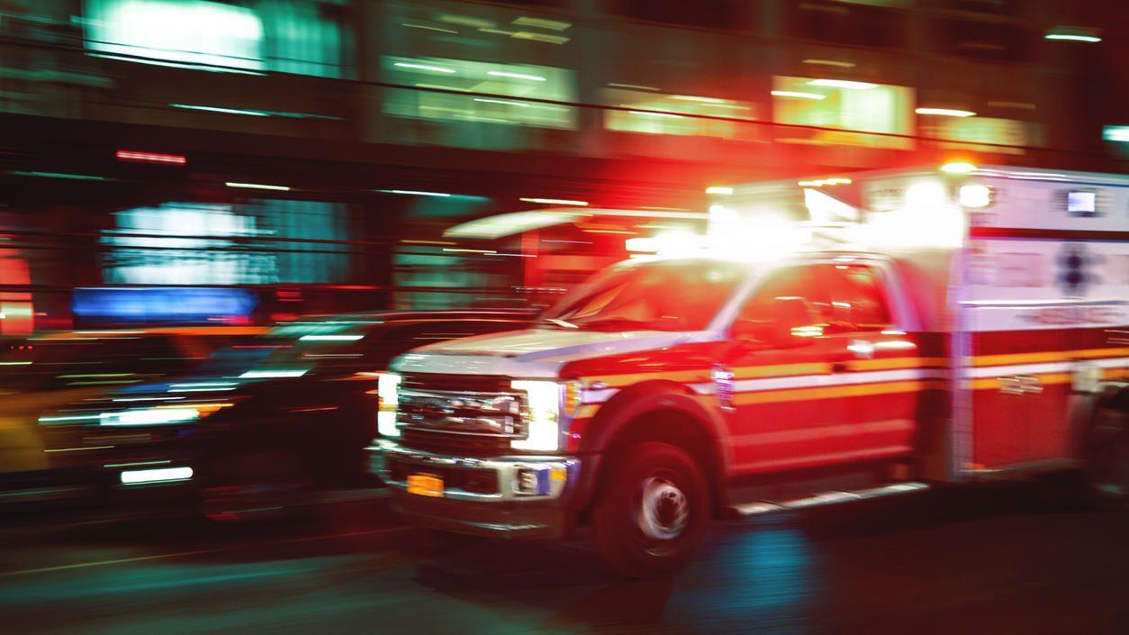 An ambulance driving down the street at night.