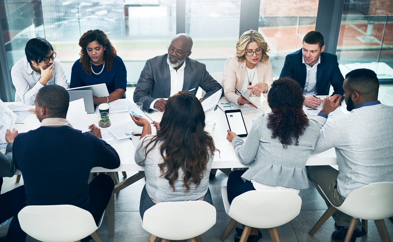 businesswoman holding tablet in front of coworkers working at their desks