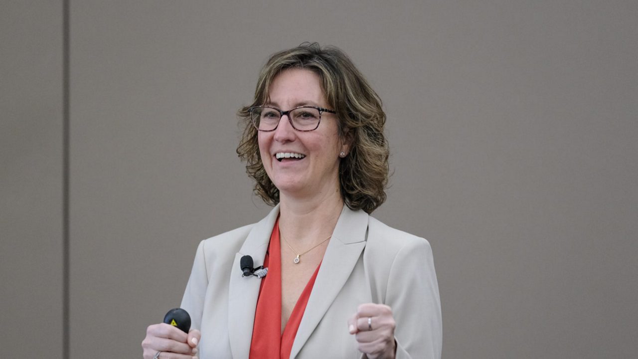 A businesswoman in glasses is giving a presentation.