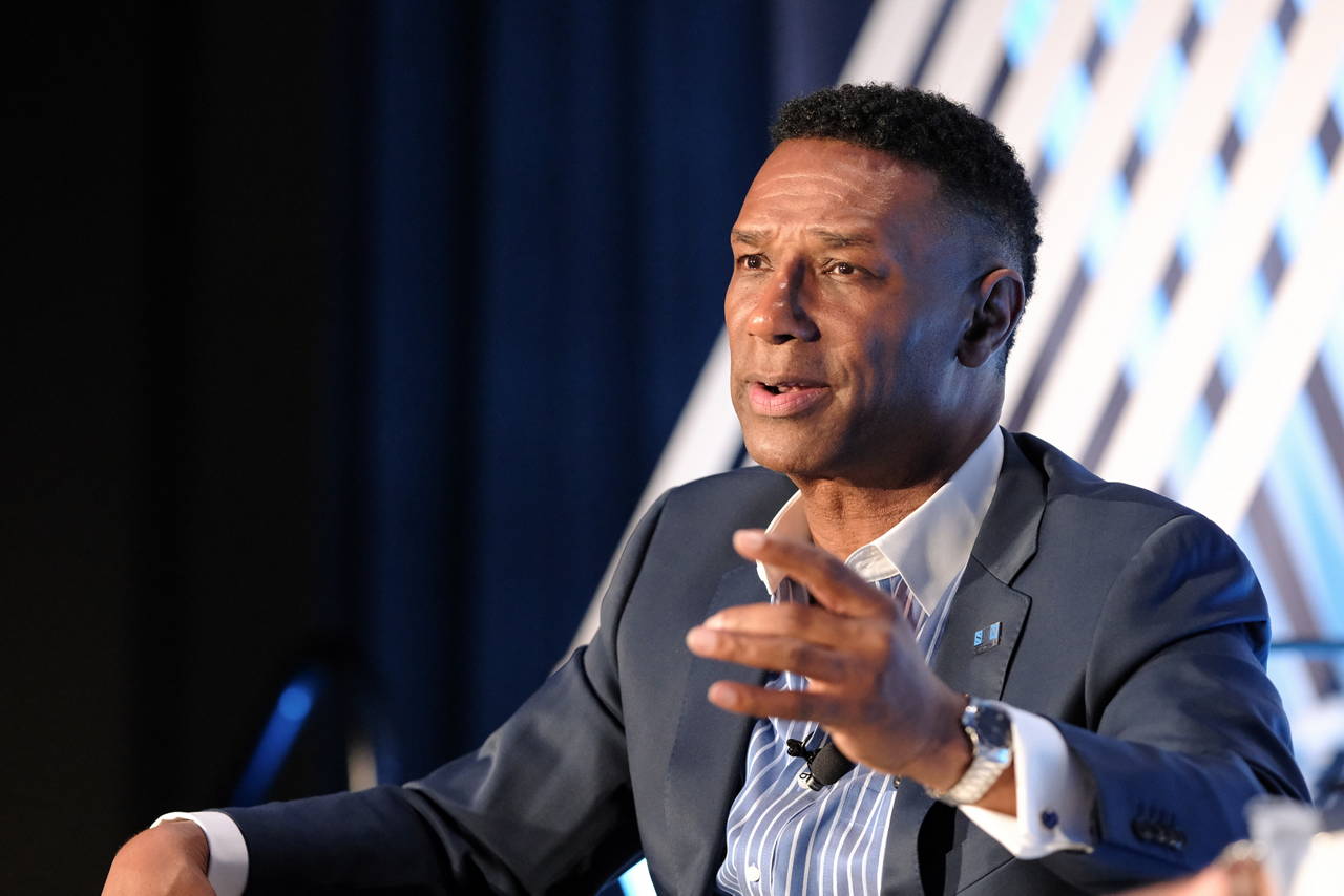 Johnny C. Taylor speaking while seated on a stage.
