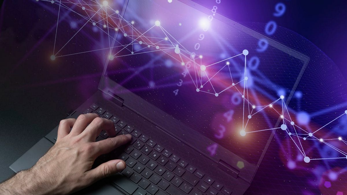 A man is typing on a laptop with a purple background.