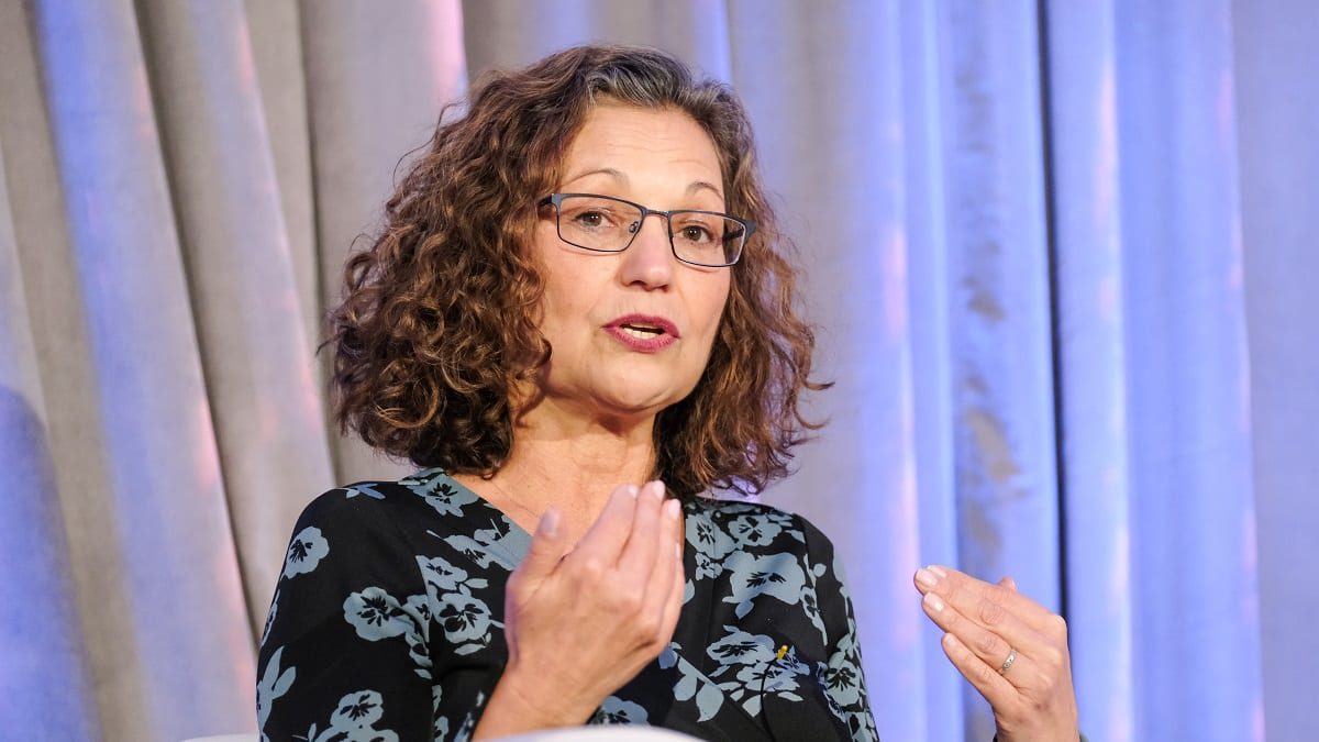 A woman in glasses sitting in a chair.