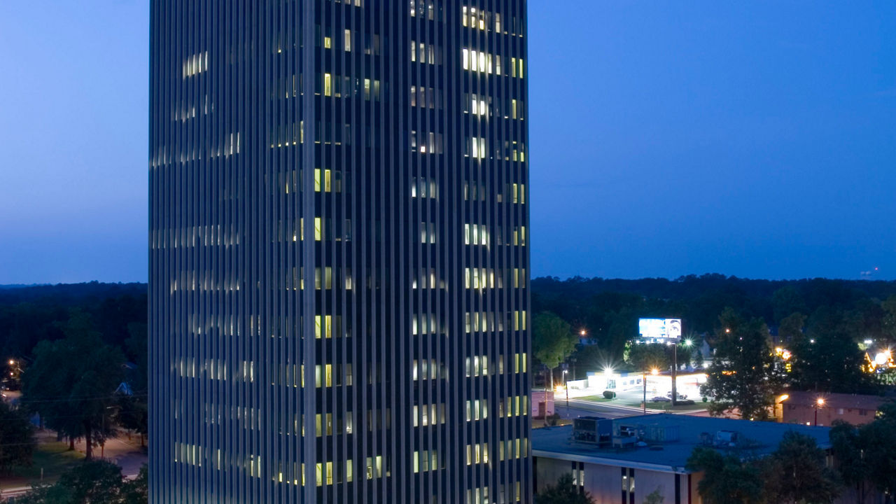 A tall building lit up at night in a city.