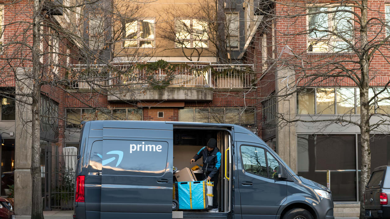 A prime delivery van is parked in front of a building.