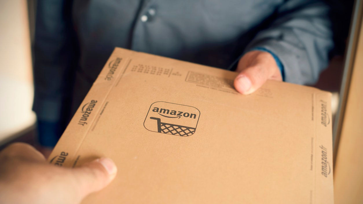 A person is handing an amazon box to another person.