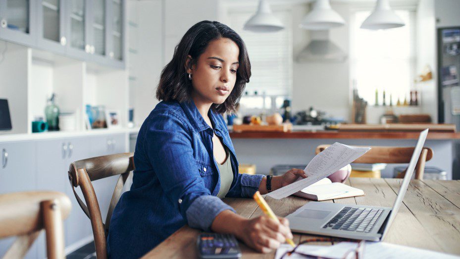 Woman works from home, in kitchen on laptop