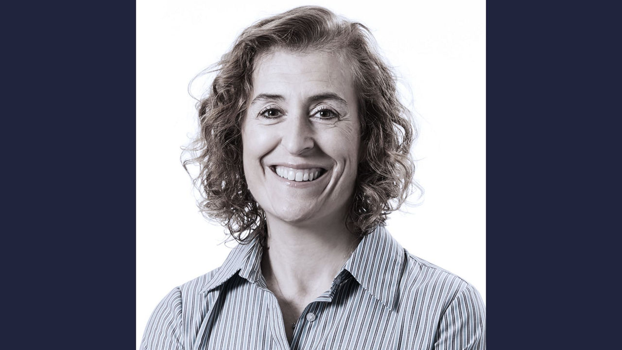 A woman with curly hair smiling for the camera.