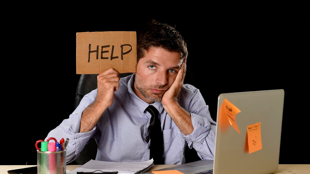 A businessman holding up a sign that says help.