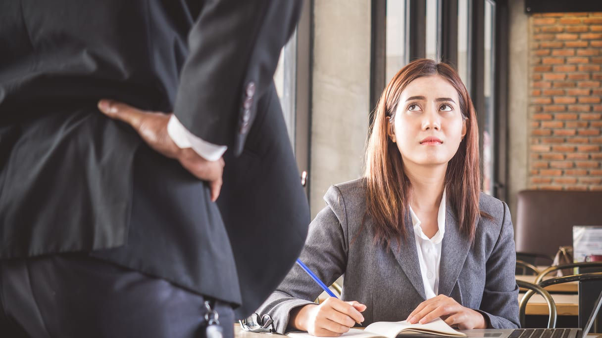 A woman in a business suit is talking to a man at a table.