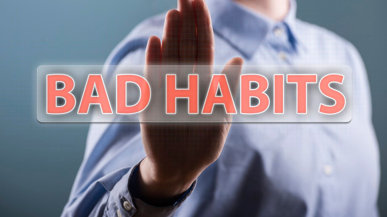 A man is holding up a sign that says bad habits.