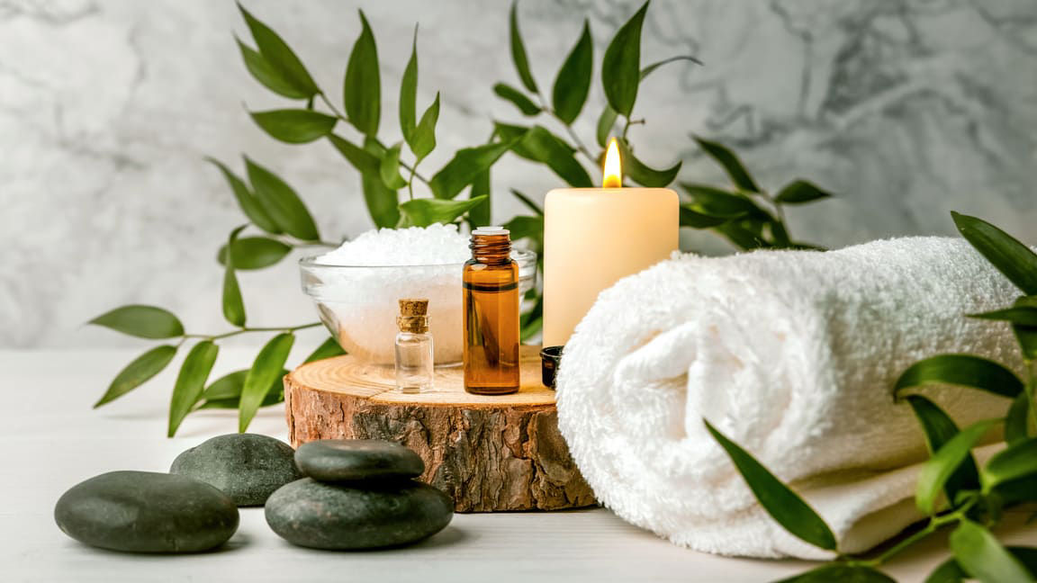 A spa table with towels, stones and a candle.